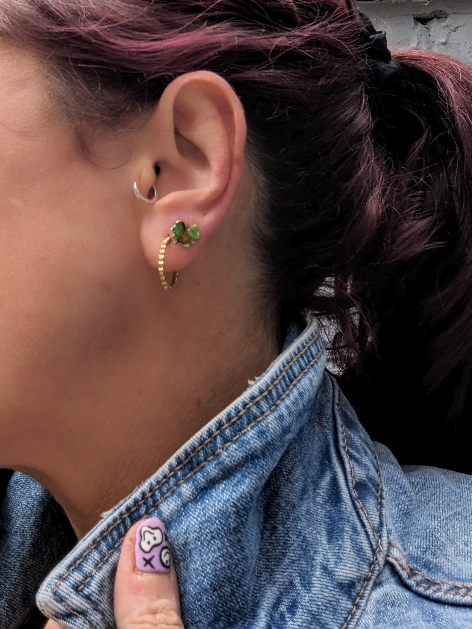 Model wearing green stud earrings. 