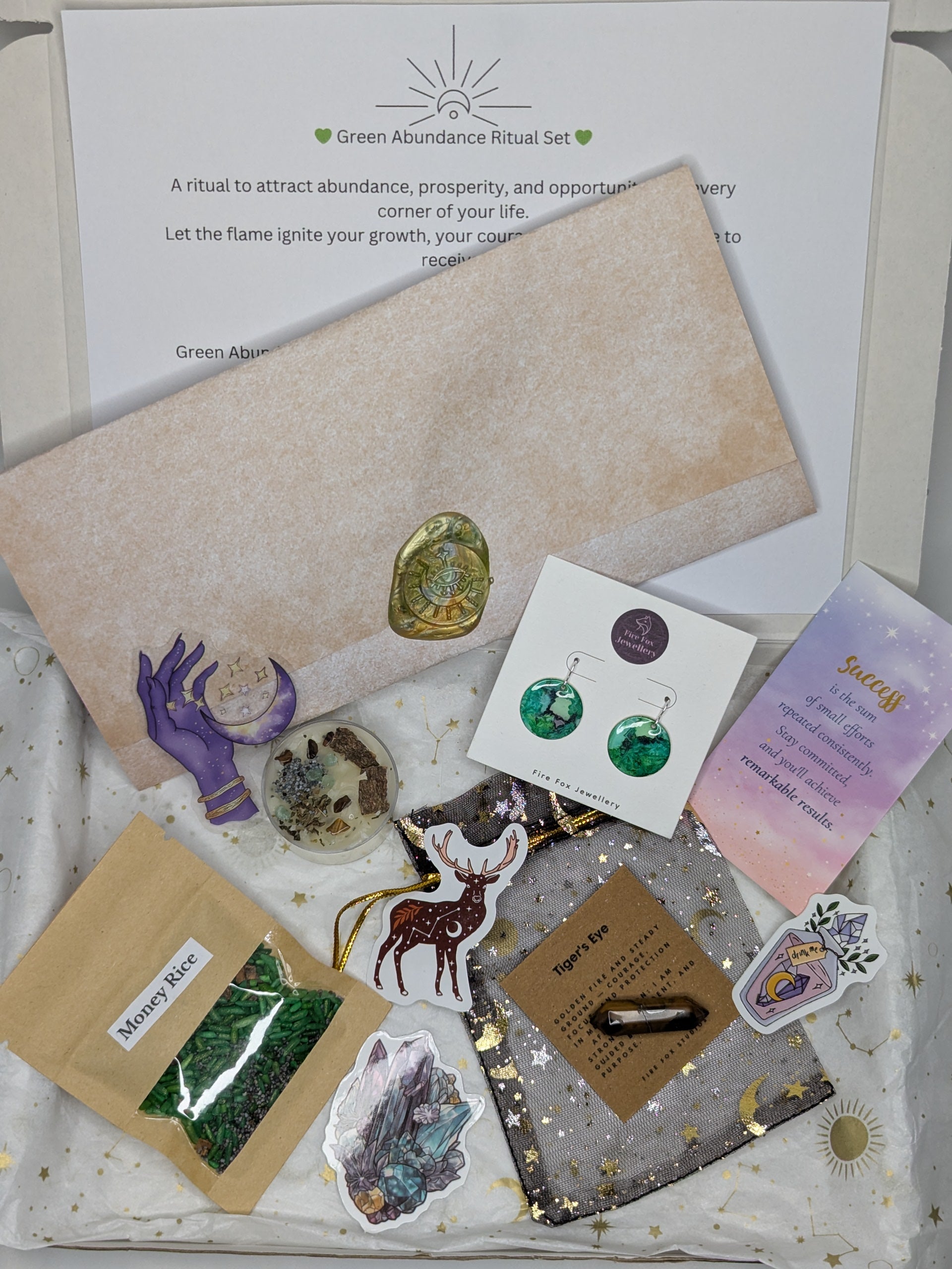 Green abundance ritual set with stones, cards, and packaging on a white surface.